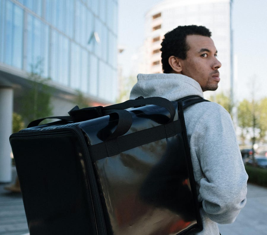 Man in Gray Hoodie Carrying Black Leather Bag